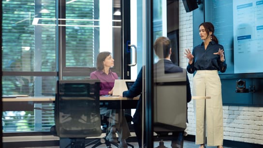 Multiple people in a meeting next to a wall electronic screen.