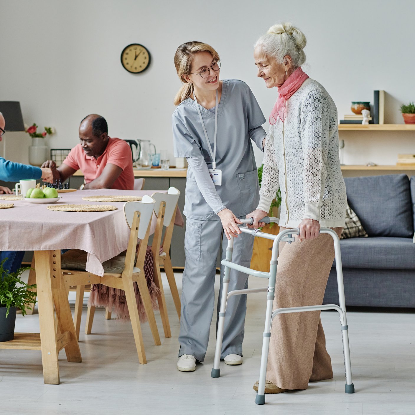 Young volunteer in uniform caring about senior people in nursing home