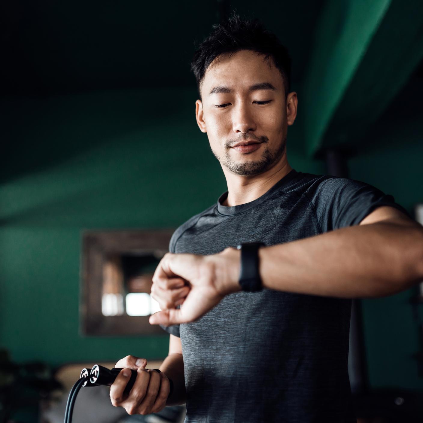 男子在家運動，使用智慧型手錶的健身追蹤器應用程式監控訓練進度