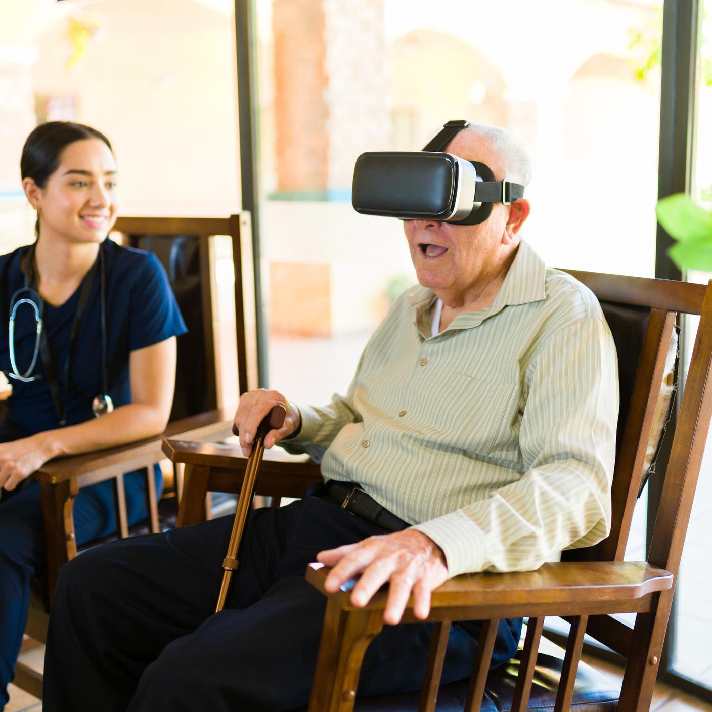 Un señor mayor se divierte en la residencia de ancianos mientras juega con gafas de realidad virtual.