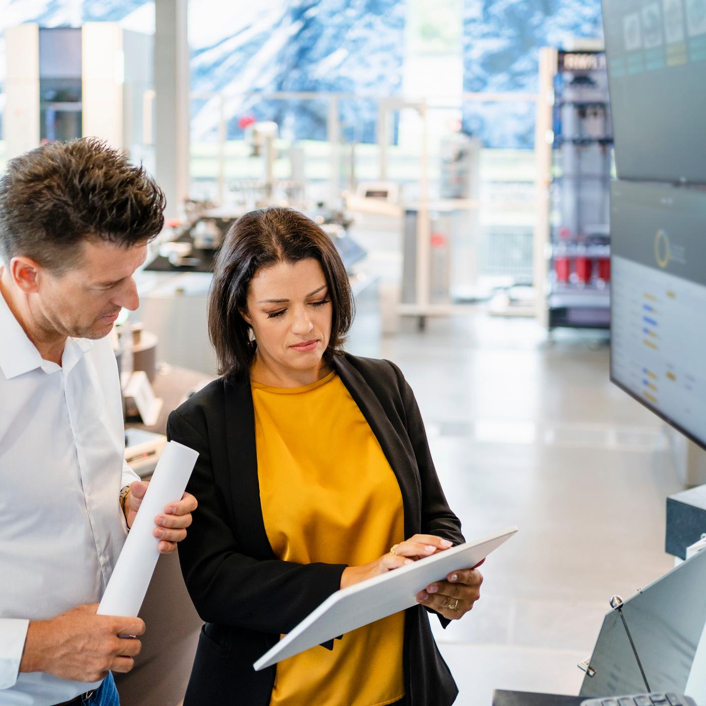 Aider l’industrie manufacturière britannique à adopter la numérisation - Une femme d’affaires utilisant une tablette PC à côté d’un collègue dans l’industrie