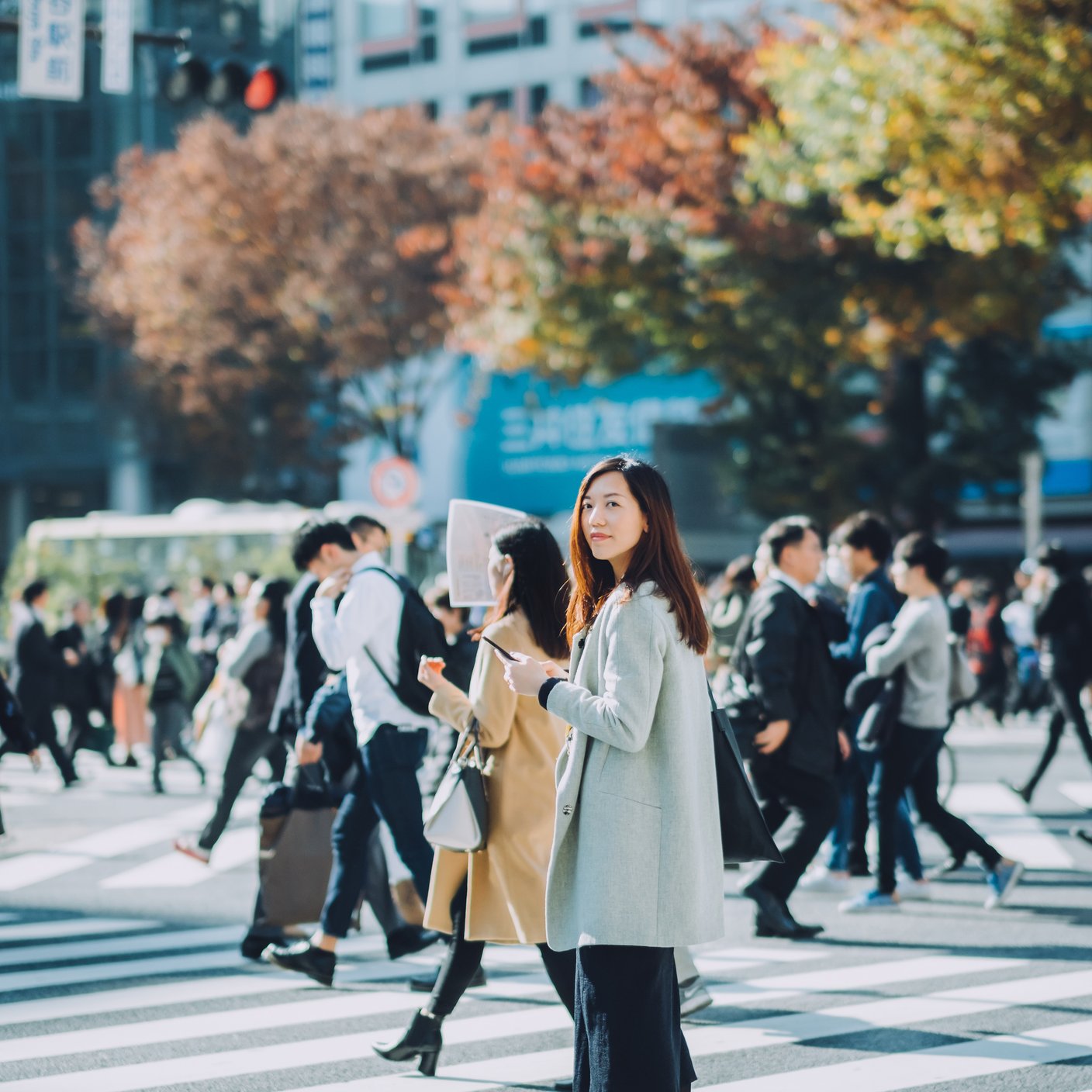 美麗的亞洲女商人在東京繁忙的街道上邊走邊使用智慧型手機