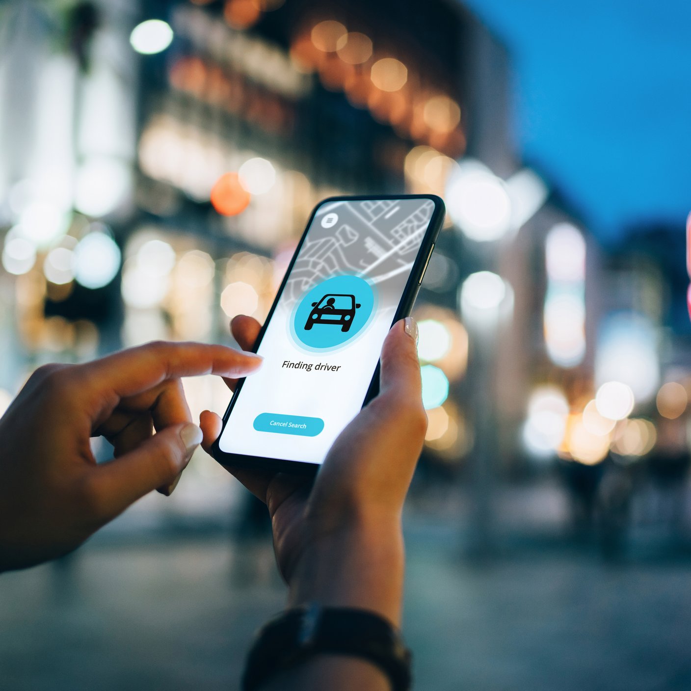 Close up of young woman using mobile app device on smartphone to arrange a taxi ride in downtown city street.