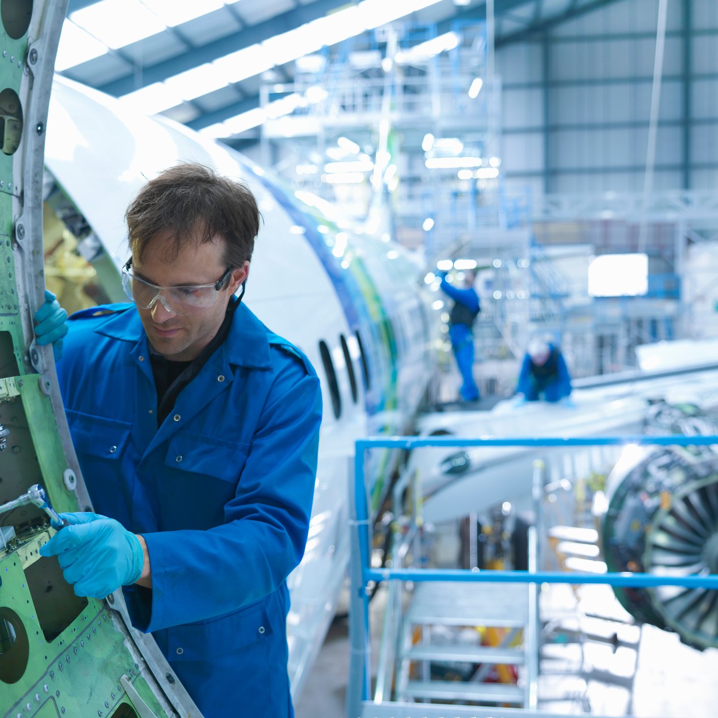 Engineer working on aircraft door in aircraft maintenance factory