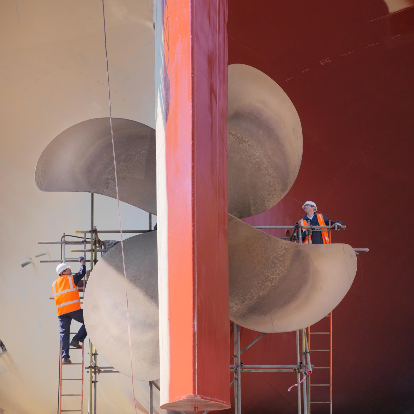 Image of Workers checking underside of ship in dry dock.