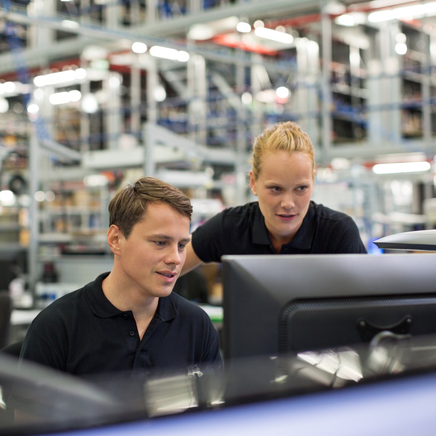 Employés utilisant un ordinateur dans un entrepôt logistique.
