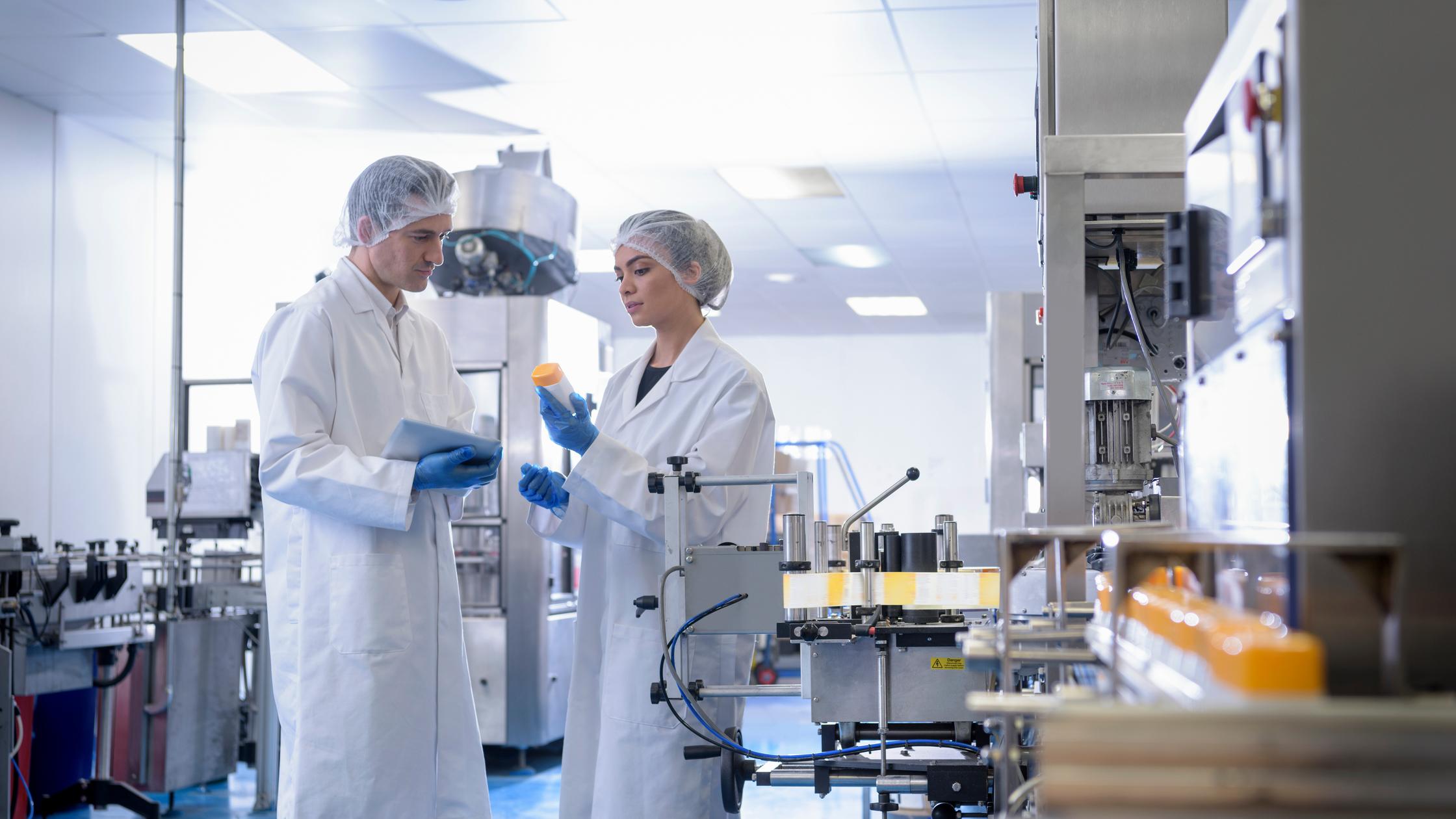 Workers inspecting product in pharmaceutical factory.
